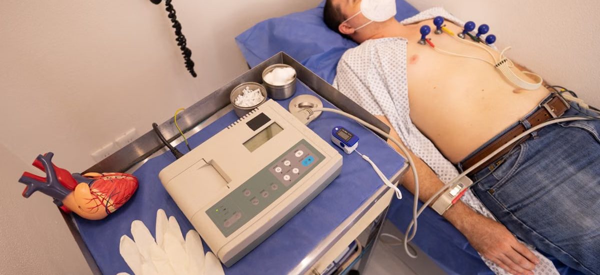 A man undergoing a cardiology exam with an ECG machine in a medical clinic.