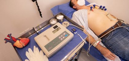 A man undergoing a cardiology exam with an ECG machine in a medical clinic.